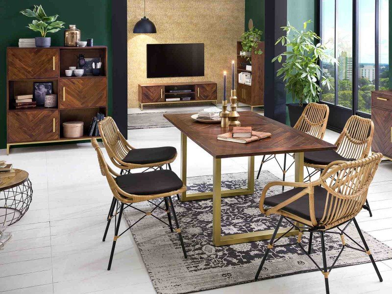 Korbstuhl aus geflochtenem Rattan auf schlankem Metallgestell in modernem, hellem Wohnambiente