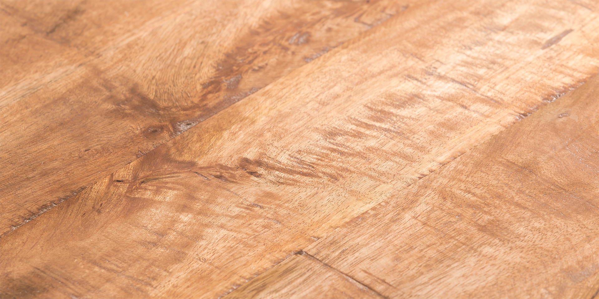 Detailaufnahme einer Landhaus-Holzoberfläche mit markanter Maserung, warmem Braunton und gealterter, rustikaler Textur