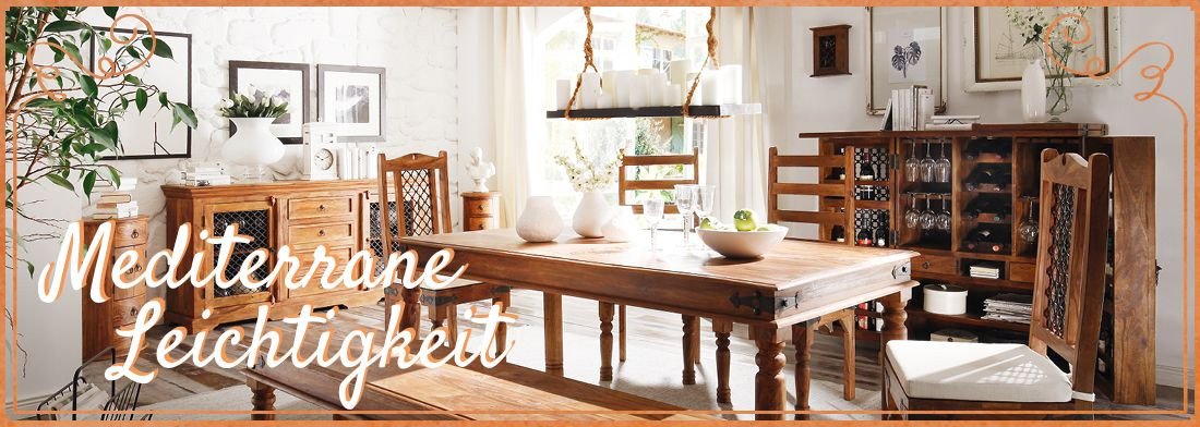 Mediterranes Wohnambiente mit hellem Holz-Esstisch, geflochtenen Stühlen, grünen Pflanzen und luftiger, sonniger Leichtigkeit