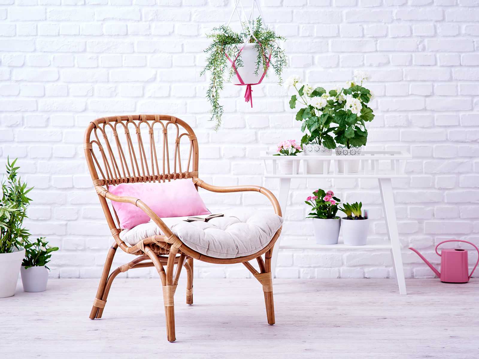 Korbstuhl mit hellem Sitzkissen in natürlichem, sonnigen Ambiente – runder Rattanstuhl im gemütlichen Boho-Stil