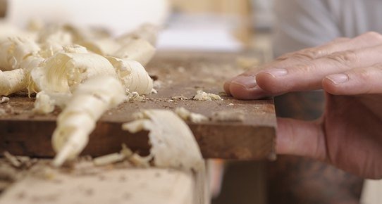 Grafik "Wissenswertes – Übersicht Oberflächen" mit beschrifteten Holzproben, verschiedenen Holzfarben und Oberflächenstrukturen in warmen Braun‑ und Grautönen.