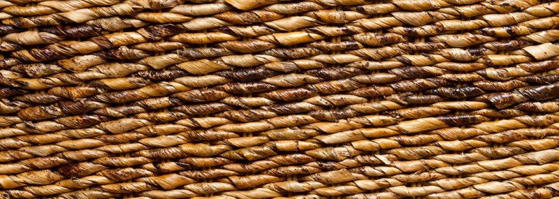 Nahaufnahme eines Holzgeflechts im Bananenblatt-Flechtmuster, warme Beige- und Brauntöne, dekoratives Möbel- und Einrichtungsdetail.