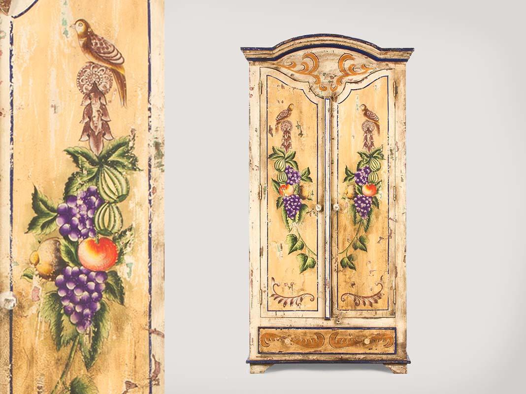 Bemalter Bauernschrank aus Holz im Landhausstil mit floraler Dekoration, warmen Pastellfarben und rustikalem Ambiente