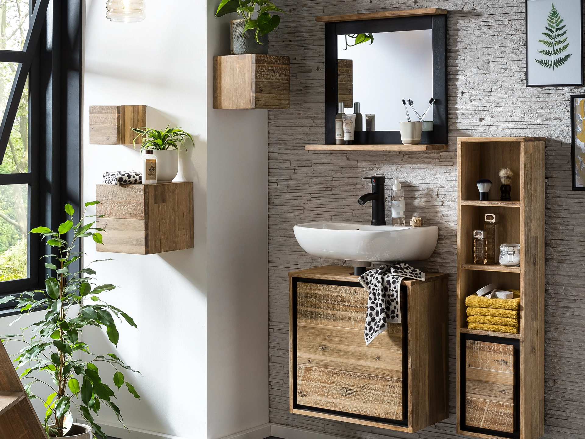 Jolo Sofa in modernem Wohnambiente, frontal gezeigt: graues Stoffpolster auf Holzboden, Dekokissen und Beistelltisch