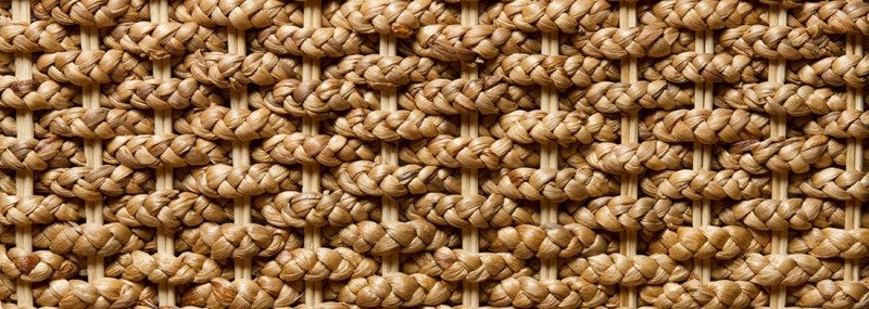 Nahaufnahme eines warmbraunen Wasserhyazinthe-Geflechts: dichtes Flechtmuster aus Naturfasern für Möbel, organische Textur.