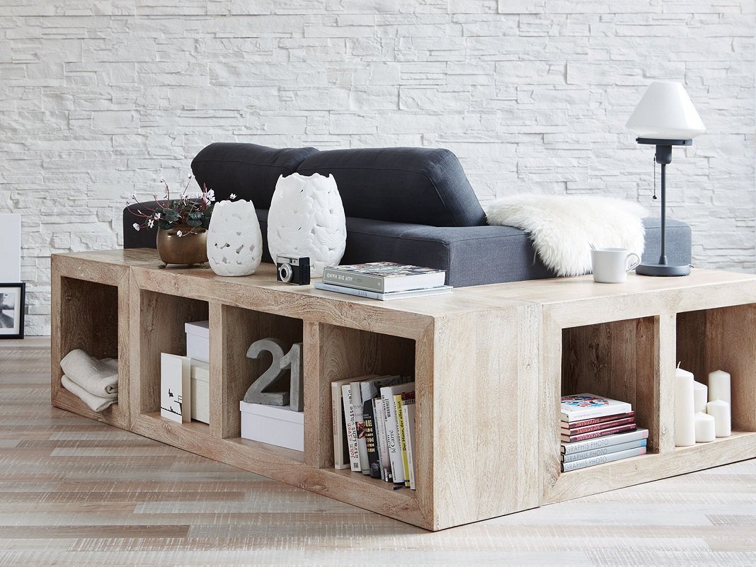 Offenes Würfelregal aus Holz als Raumteiler im Wohnzimmer, helle Holzoptik, Fächer mit Pflanzen und Büchern.